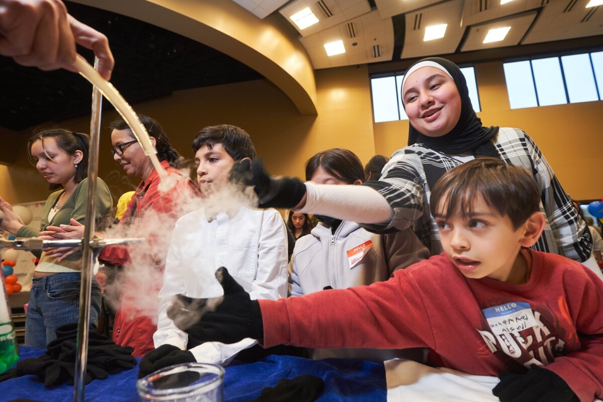 A group of kids interacting with science as part of Pi Day, an annual community event for students to see STEAM as a possible career path